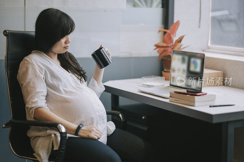 an asian chinese pregnant woman working from home during the lock down checking on her message using her phone taking a break in her home office